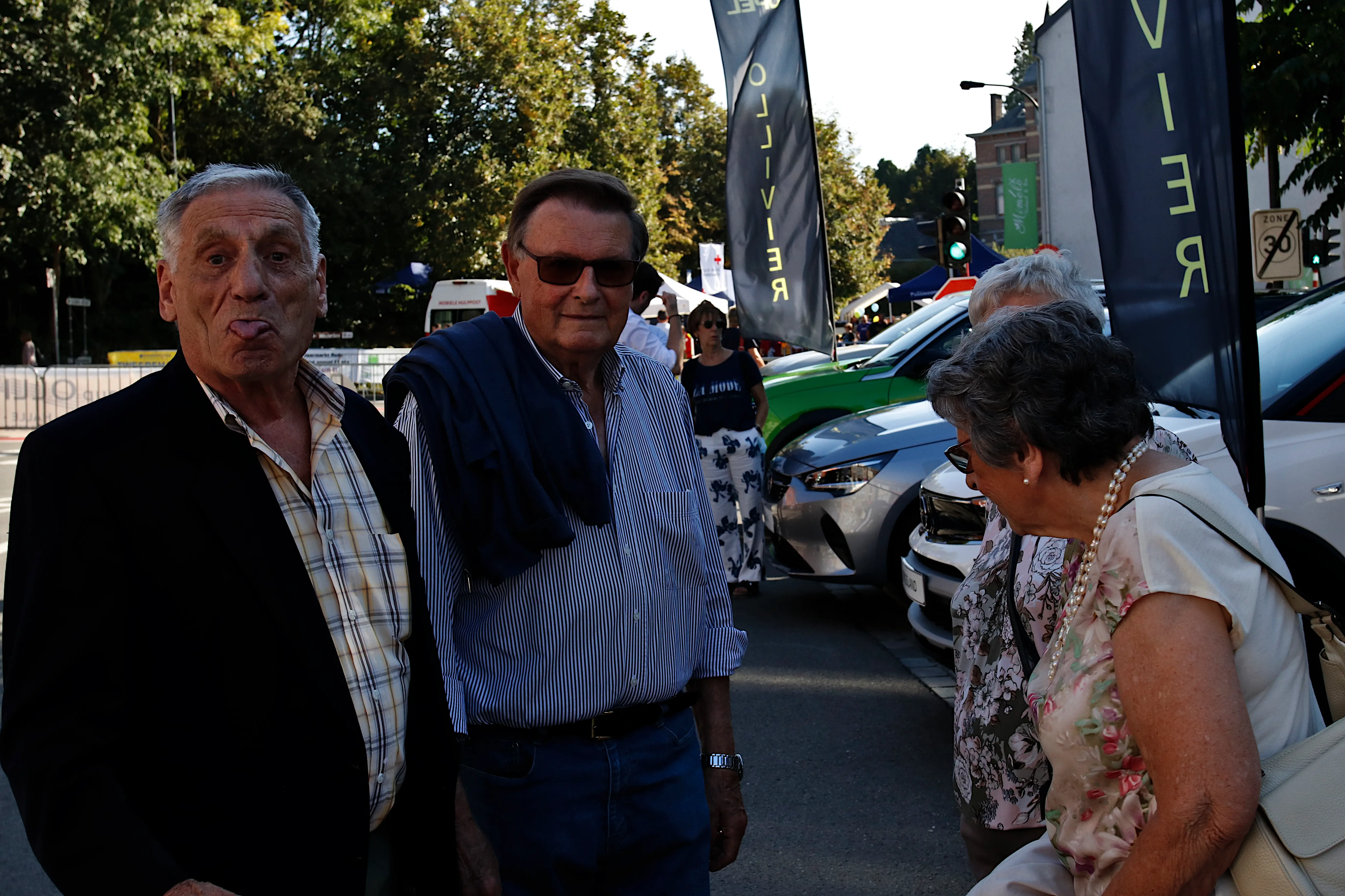 4 mensen aan het genieten aan de parking van de Jaarmarkt van Rode, 1 man steekt zijn tong uit